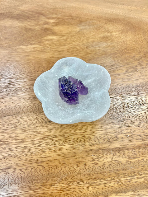 Elegant Selenite Flower Bowl with a crystal placed in the center, on a wood background.