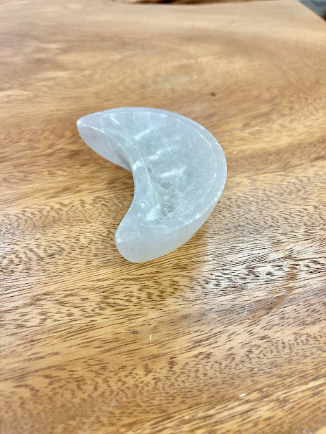 Side view of the Selenite Moon Bowl on wood, showcasing its depth and unique moon design.
