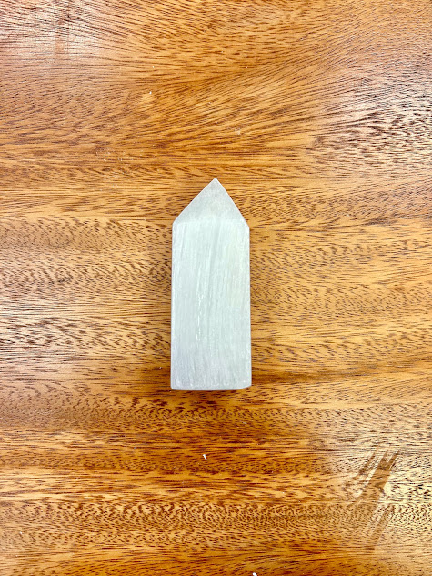 The Selenite Obelisk standing alone, casting a gentle shadow, indicative of its calming properties.
