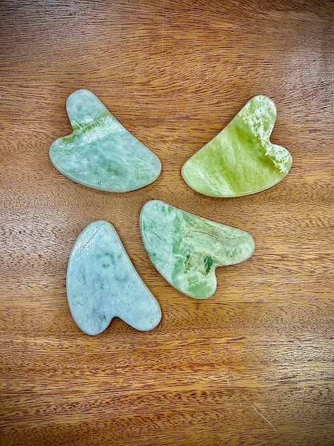 Assorted collection of Gua Sha tools showcasing different natural shades of jade.