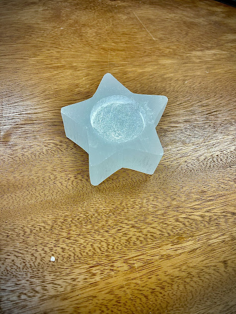 Empty Selenite Star Candle Holder on a wooden surface, showcasing its natural, ribbed texture.